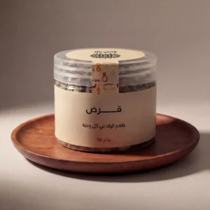 عبوة شفافة فاخرة لمنتج "قرض سدرة" بوزن 150 جرام، مغلفة بملصق (ليبل) كريمي أنيق يحمل شعار سدرة وعبارة "طعم البلد في كل وجبة". العبوة موضوعة بوضعية مركزية على صينية خشبية دائرية، مع إضاءة دافئة تبرز جودة ثمار القرض الطبيعية بداخلها.