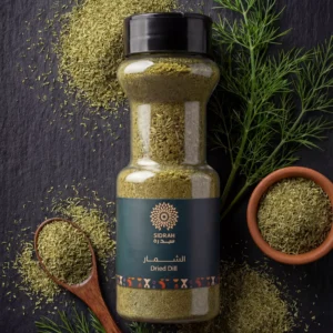 "الشِمار المجفف" من سدرة. تظهر زجاجة شفافة أنيقة بداخلها شِمار أخضر عالي الجودة، يحيط بها مسحوق الشِمار المنثور، وملعقة خشبية، ووعاء فخاري صغير، مع أغصان شبت طازجة. الخلفية سوداء رخامية تبرز لون المنتج الزاهي وتصميمه العصري.