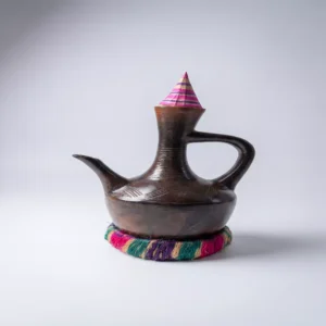 دلة قهوة سودانية (جبنة) مصنوعة من الفخار البني المصقول مع قاعدة منسوجة يدوياً بألوان زاهية وتصميم تقليدي أنيق